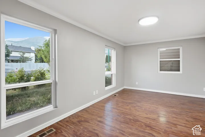 Wood-finish flooring with white trim, multiple windows, and a flush-mount ceiling light