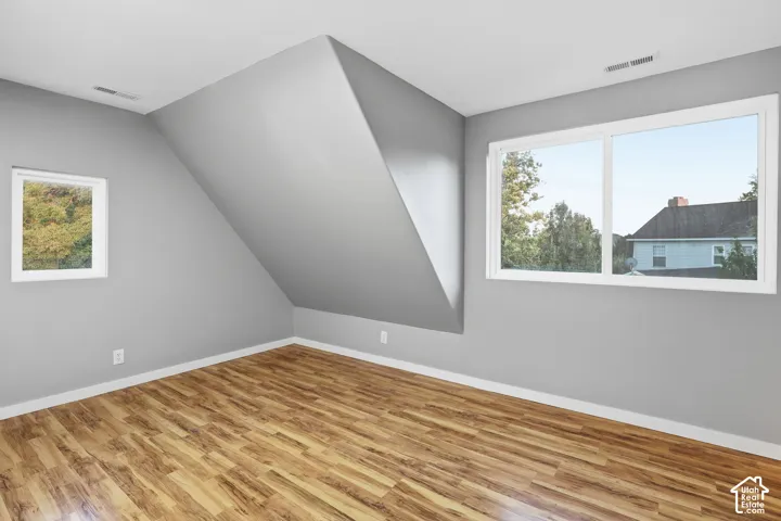 Wood-finish flooring, white trim, and two windows provide natural light