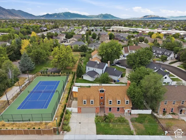 Brick exterior residence with dormer windows, attached garage, private tennis court, and mature landscaping