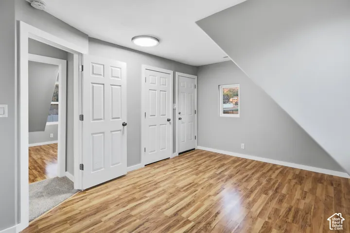 Wood-finish flooring with light gray walls, multiple paneled doors, and a ceiling-mounted light fixture