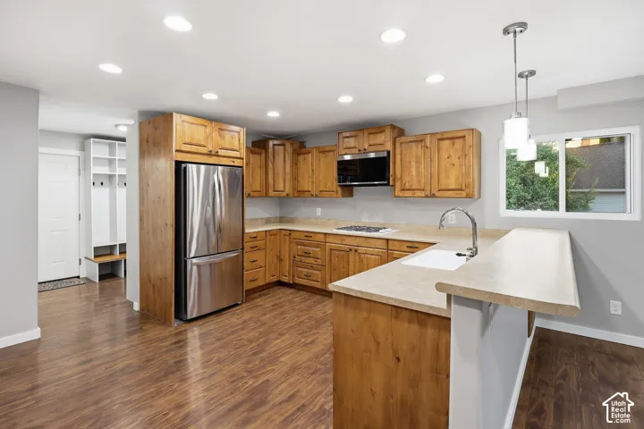 Kitchen featuring wood-finish cabinetry, stainless steel appliances, a breakfast bar, recessed lighting, and wood-finish flooring