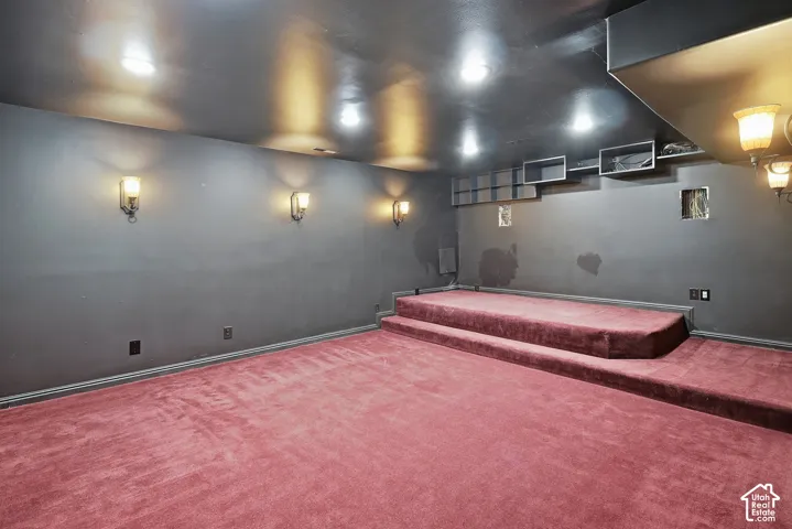 Carpeted flooring, recessed ceiling lighting, wall-mounted sconce lighting, and built-in shelving
