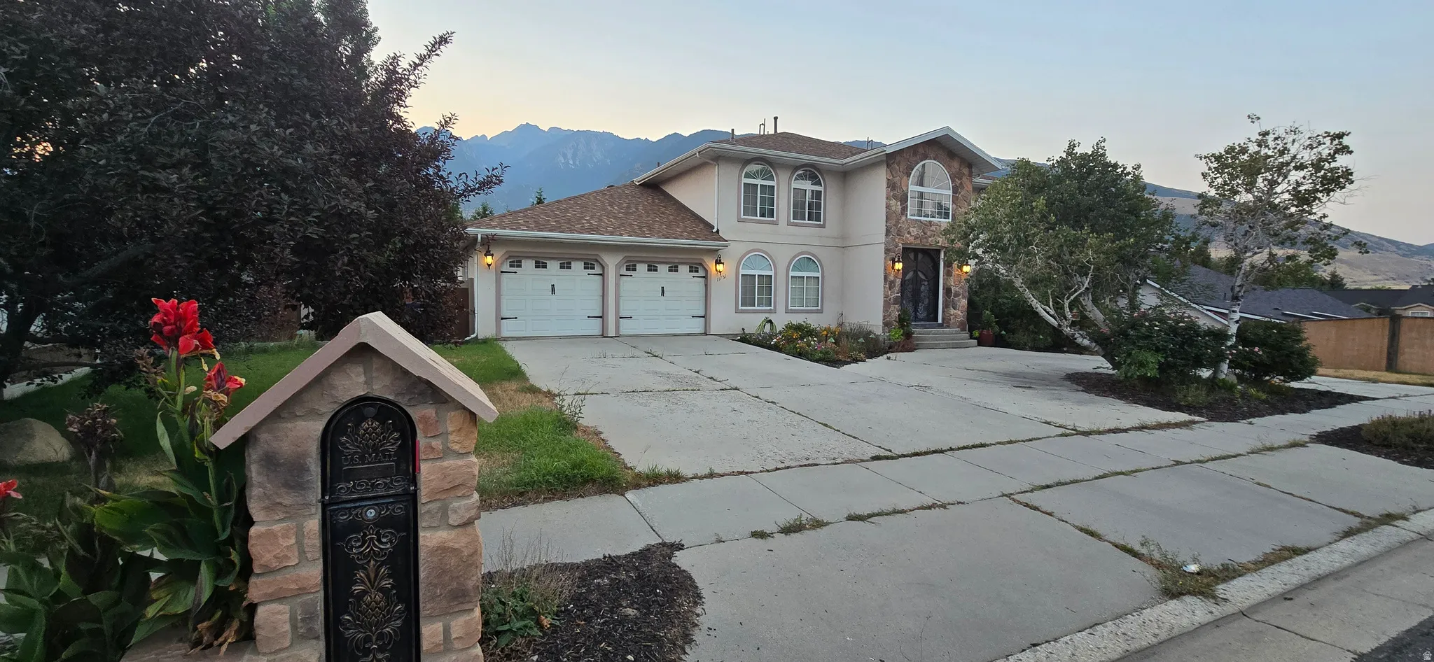 Two-story residence featuring a two-car garage, stone and stucco exterior, and arched windows