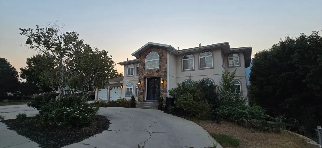 Stucco exterior with stone accents, arched windows, an attached three-car garage, and a concrete driveway