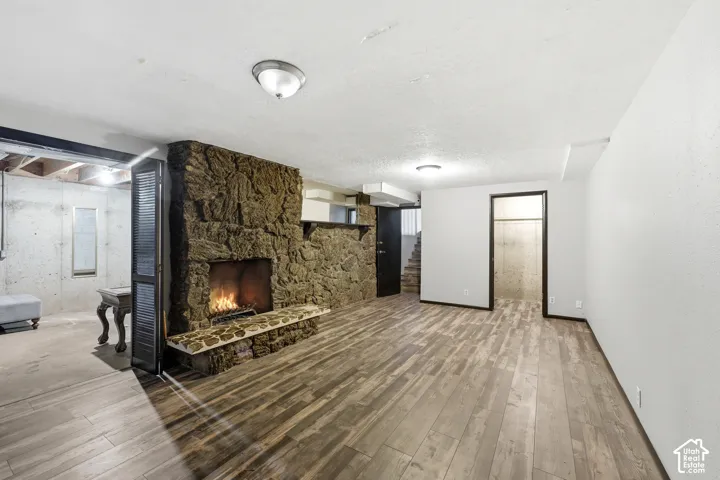 Stone-clad fireplace with hearth, wood-finish flooring, recessed lighting, and white walls