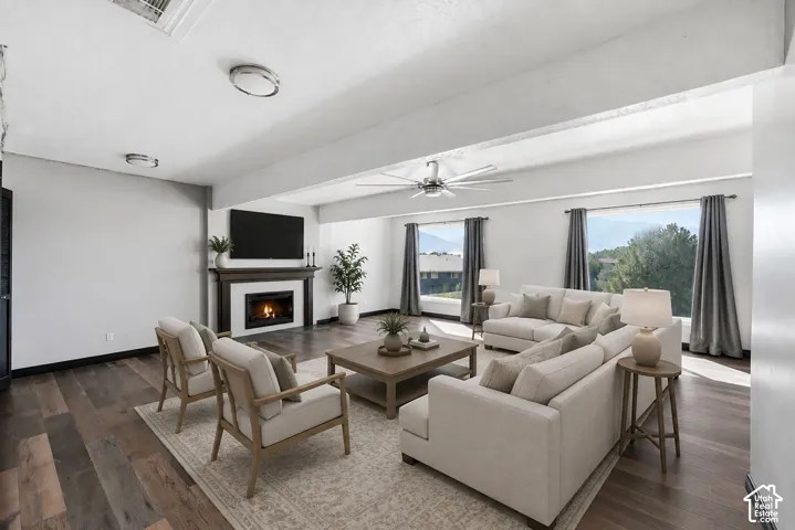 Wood-finish flooring throughout, fireplace with dark wood mantel, contemporary ceiling fan, recessed ceiling lights, and multiple large windows