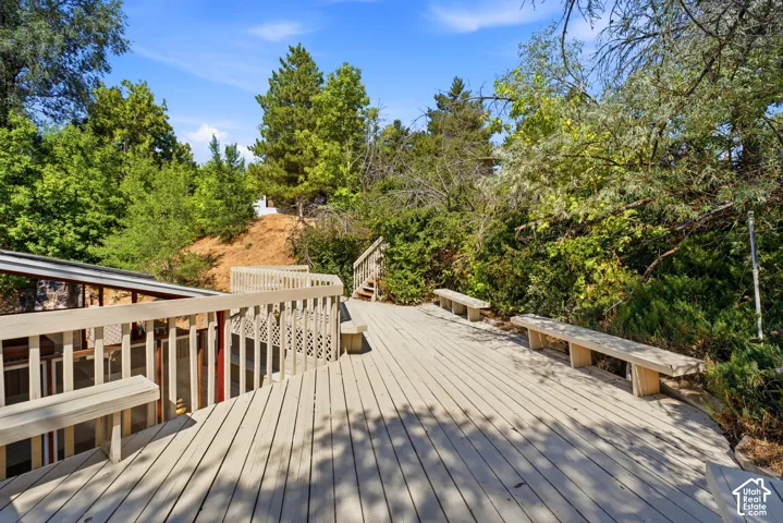Expansive outdoor deck with integrated seating, slatted railings, and lush surrounding foliage