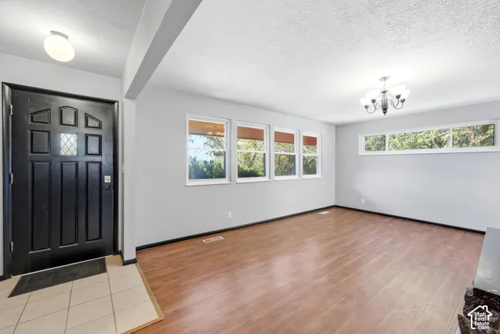Entryway with tile flooring, wood-finish flooring, multiple windows, and a decorative chandelier