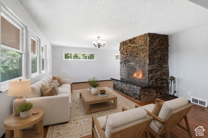 Expansive living area featuring a prominent stone-clad fireplace with a hearth, multiple windows, and wood-finish flooring
