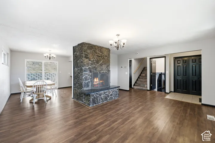 Central stone fireplace with hearth, wood-finish flooring, and chandelier lighting