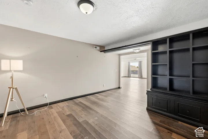 Wood-finish flooring throughout, recessed ceiling light fixture, and built-in shelving with lower cabinet storage