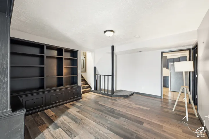 Built-in shelving unit with lower cabinetry, wood-finish flooring, and a staircase with a railing