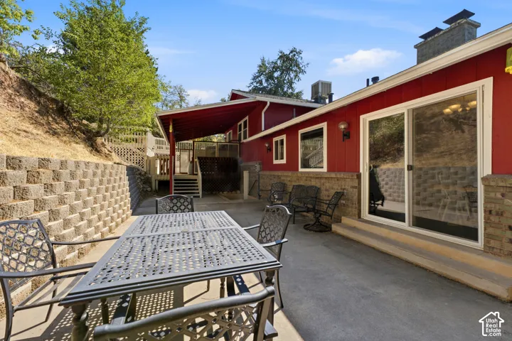Paved patio area, retaining wall, covered walkway, large sliding glass door, and exterior lighting fixtures