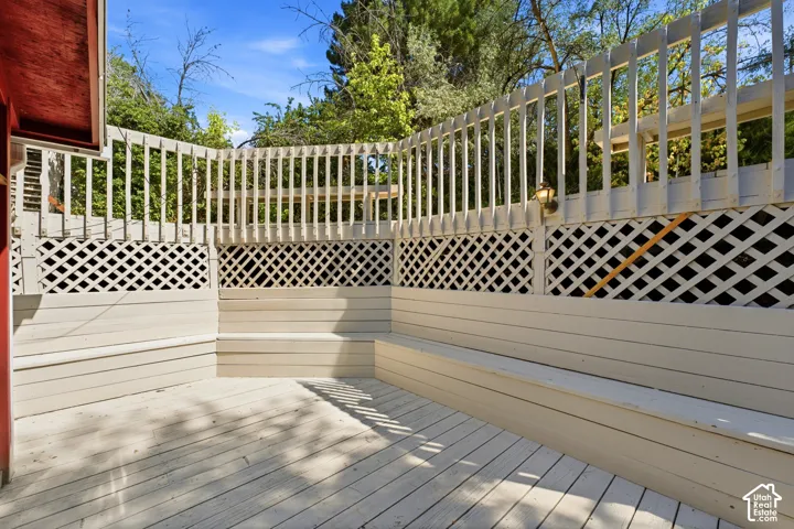 Expansive outdoor deck featuring painted wood construction, integrated bench seating, lattice detailing, and a perimeter railing