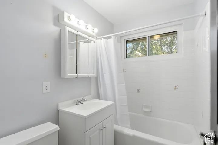 White vanity with integrated sink, chrome faucet, and mirrored medicine cabinet