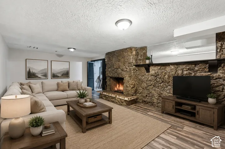 Stone-clad fireplace with hearth, wood-finish flooring, and recessed lighting