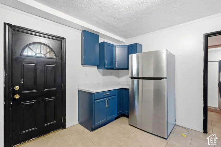 Compact kitchen area featuring blue cabinetry, white countertops, and a stainless steel refrigerator