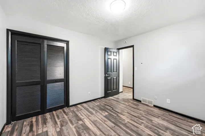 Wood-finish flooring with light-toned walls, contrasting black trim, louvered closet doors, and recessed ceiling lighting
