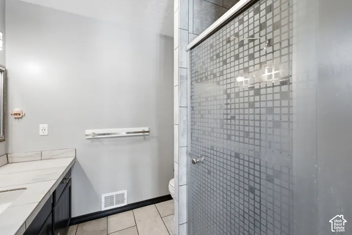 Shower enclosure with patterned glass, tile surround, and brushed nickel hardware