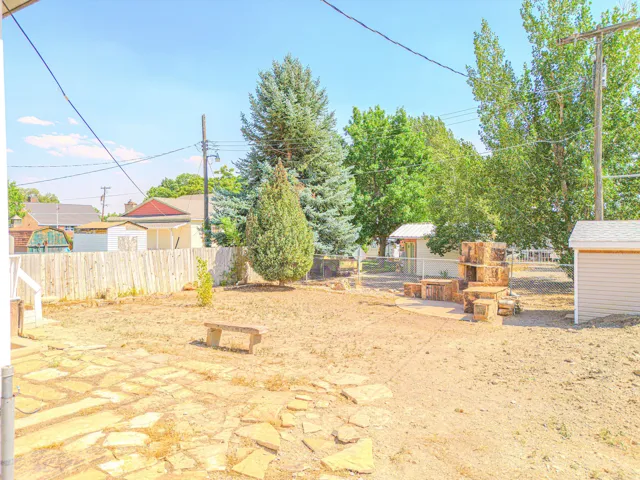 Expansive backyard featuring a partial privacy fence, chain-link fencing, a flagstone patio area, and mature trees