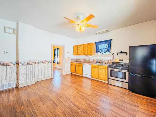 Kitchen featuring wood-finish flooring, oak cabinetry, stainless steel range, and a ceiling fan with integrated lighting