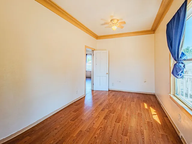 Wood-finish flooring, crown molding, and a ceiling fan with integrated lighting