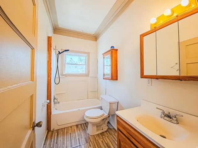 Tub-shower combination with a window, wood-finish vanity with an integrated sink, and a mirrored medicine cabinet