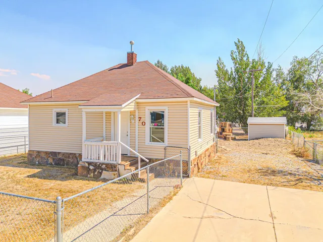 Exterior featuring light-colored siding, a covered front porch, and a shingle roof