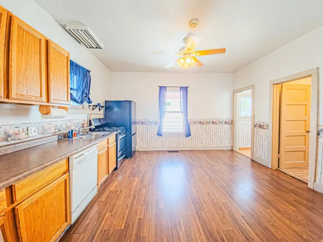 Large kitchen featuring wood cabinetry, built-in dishwasher, and a ceiling fan with integrated lighting