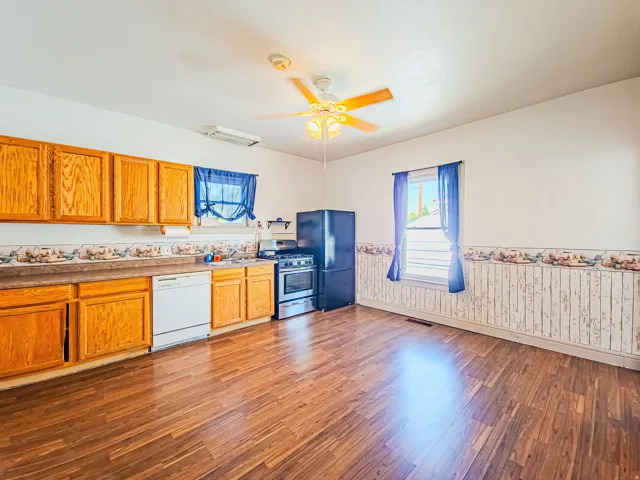 Large kitchen with wood cabinetry, built-in dishwasher, built-in range, and ceiling fan
