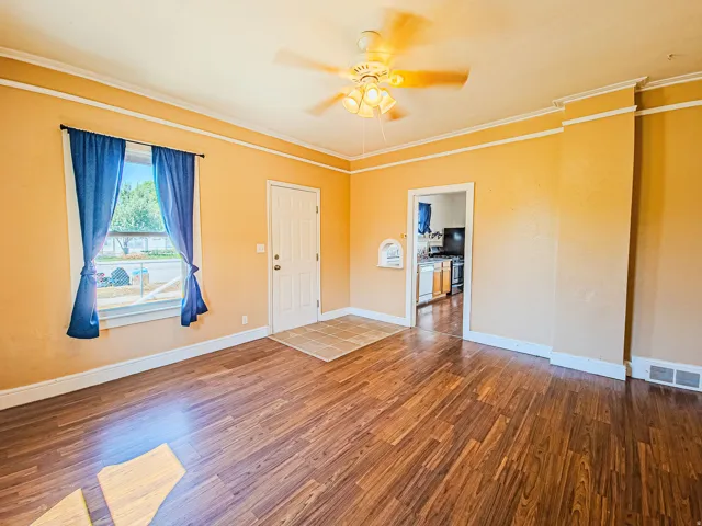 Wood-finish flooring throughout, ceiling fan with integrated lighting, and crown molding
