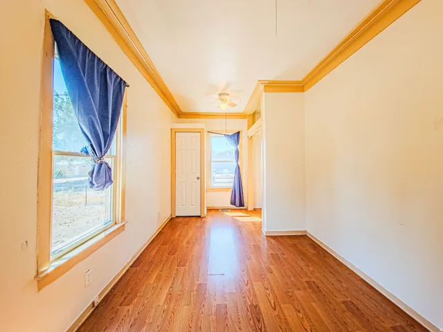 Wood-finish flooring, white walls, and wood-trimmed windows
