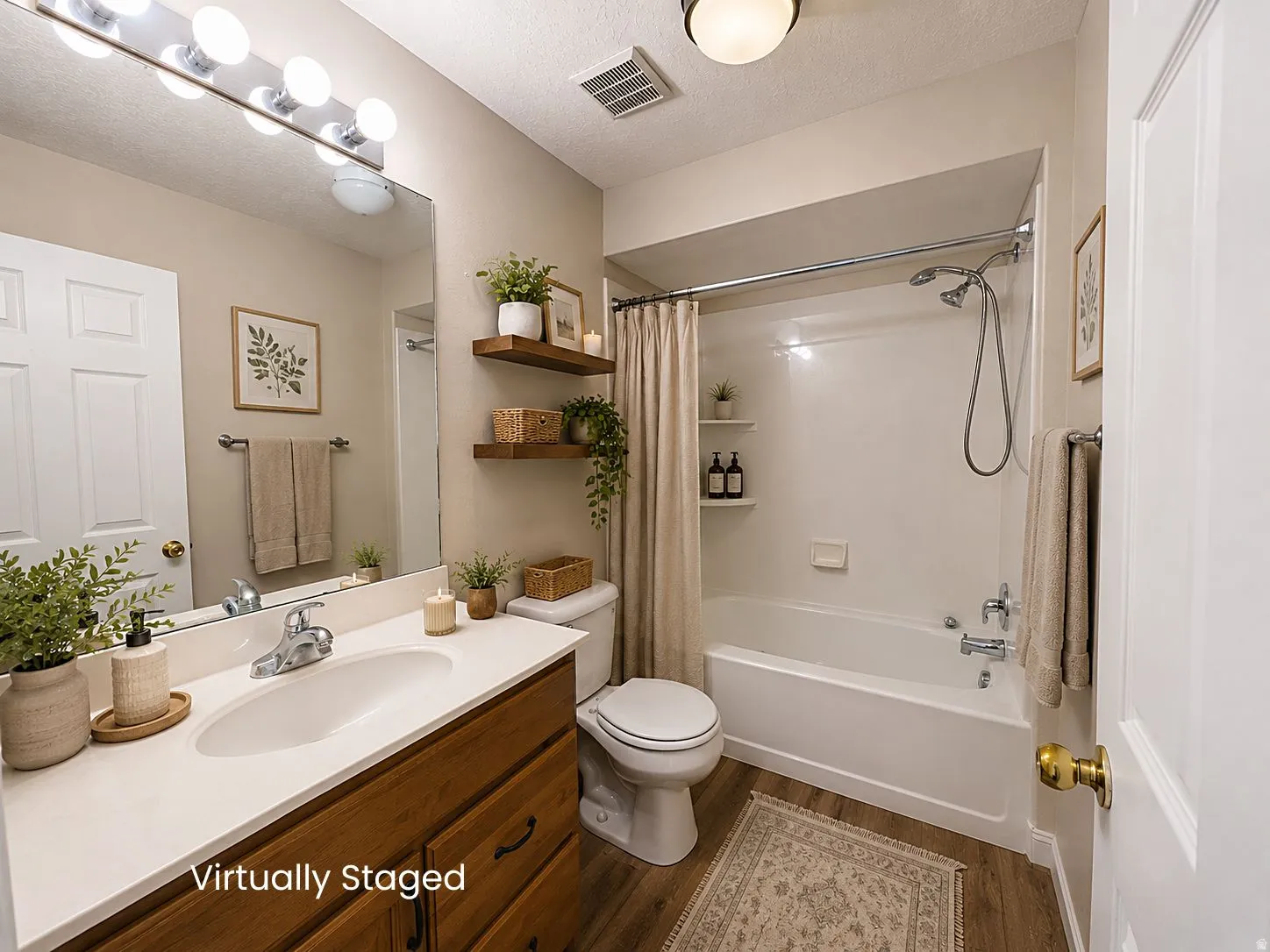 Bathroom featuring a wood-finish vanity with a single basin sink, full-width mirror, and a shower-over-tub combination with a wall-mounted showerhead