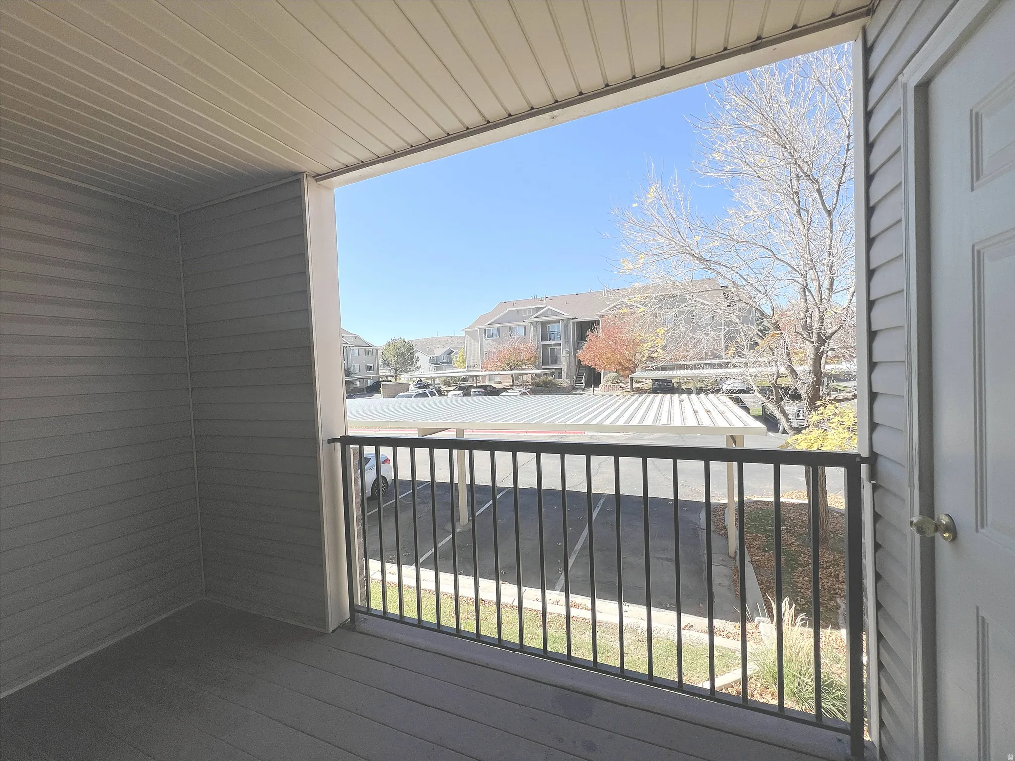 Covered balcony with black metal railing and textured siding