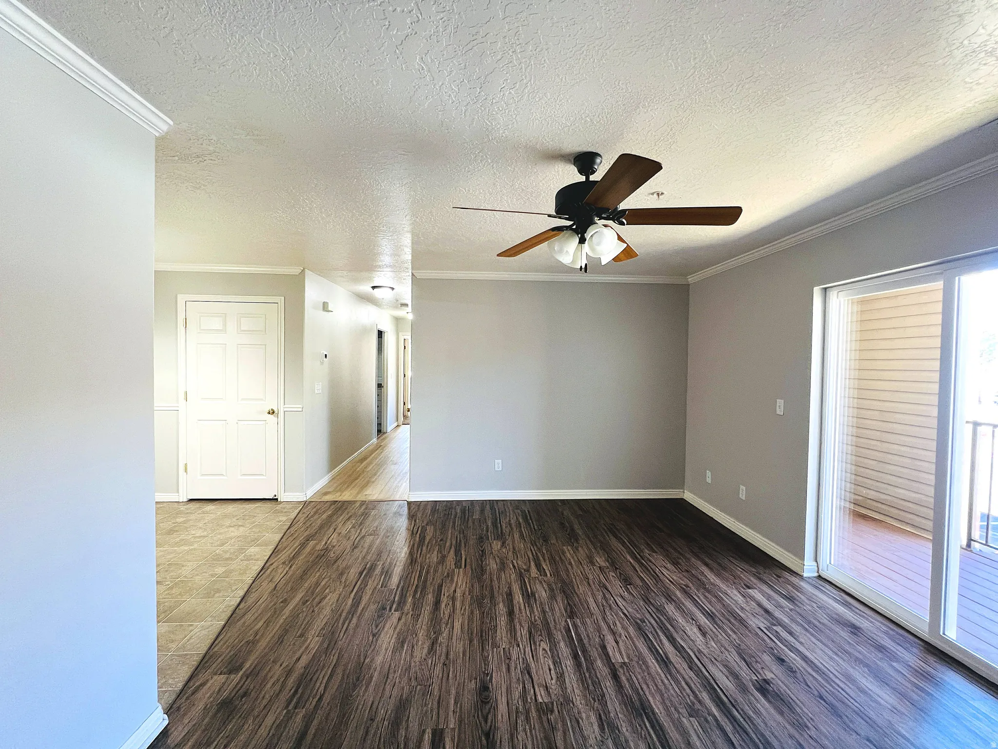 Spacious room with wood-finish flooring, light grey painted walls, and crown molding