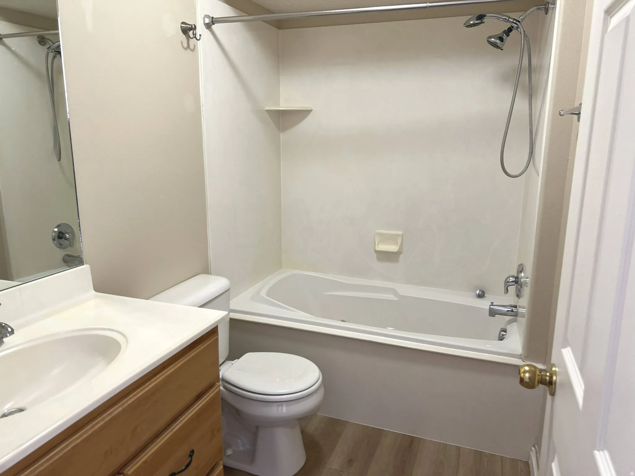 Wood-finish flooring, integrated vanity sink, wood-finish vanity with drawer storage, and a shower/tub combination with chrome fixtures