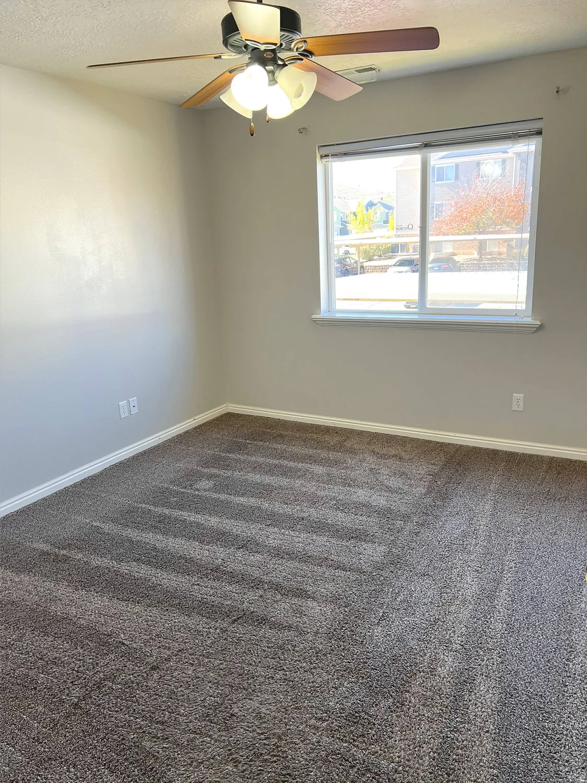 Neutral wall paint, ceiling fan with light fixture, white trim, and carpeted flooring