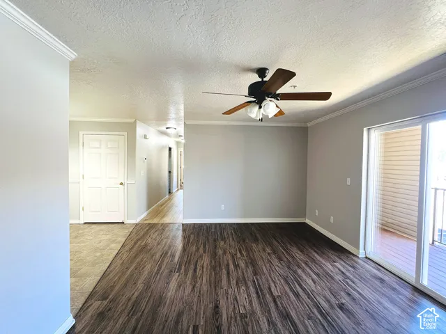 Spacious room with wood-finish flooring, light grey painted walls, and crown molding