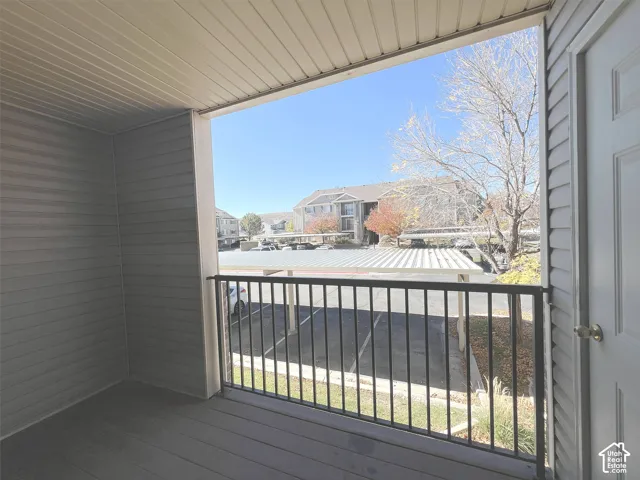 Covered balcony with black metal railing and textured siding