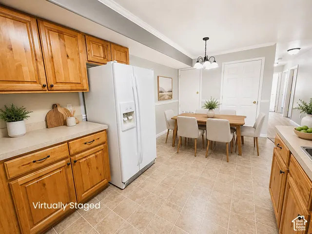 Kitchen with light wood cabinetry, white appliances, and a dining area featuring a chandelier