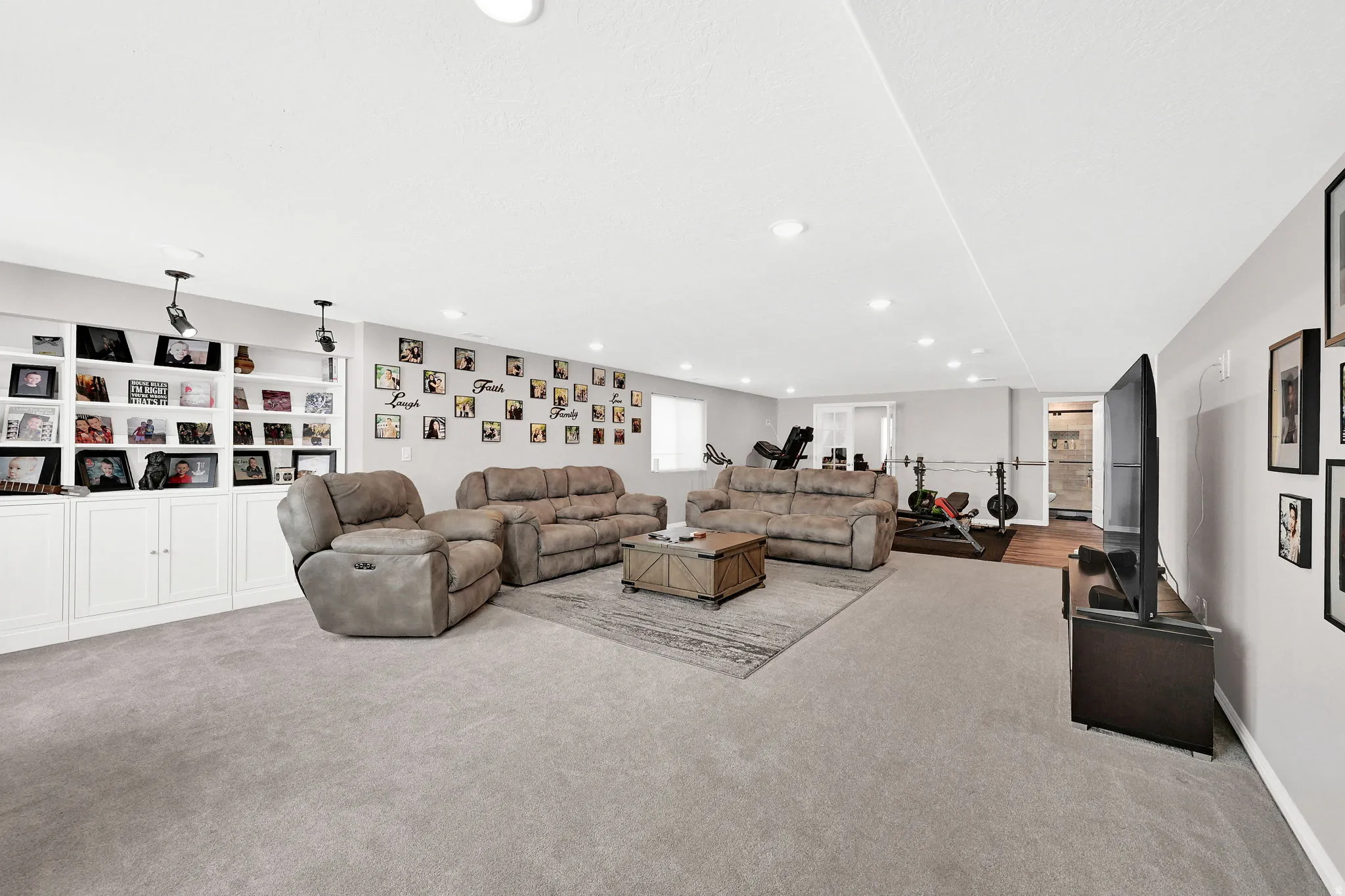Expansive room featuring recessed lighting, built-in white cabinetry with open shelving, and light gray wall paint