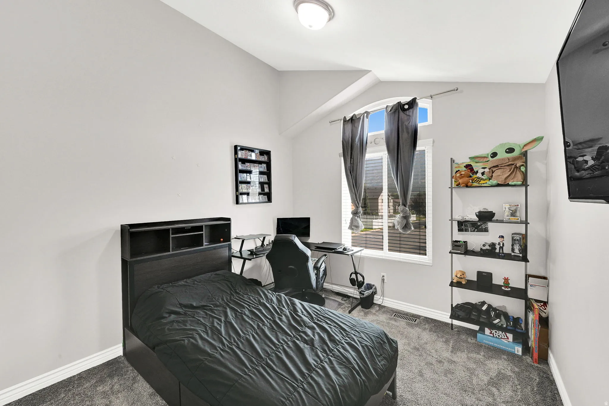 Vaulted ceiling with a recessed window, light-toned wall paint, and textured carpeting