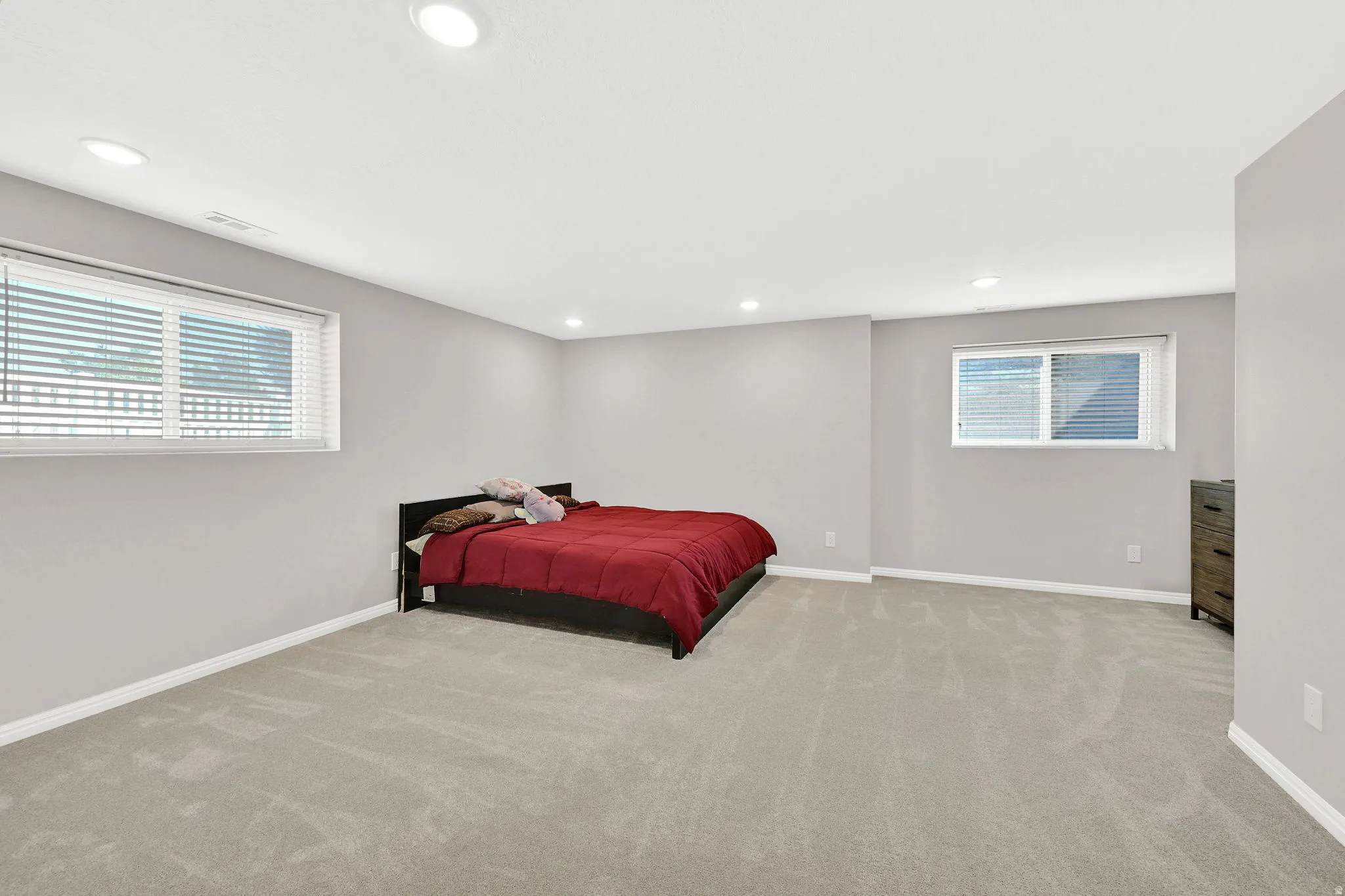 Spacious room featuring neutral carpeting, recessed lighting, and two windows with blinds