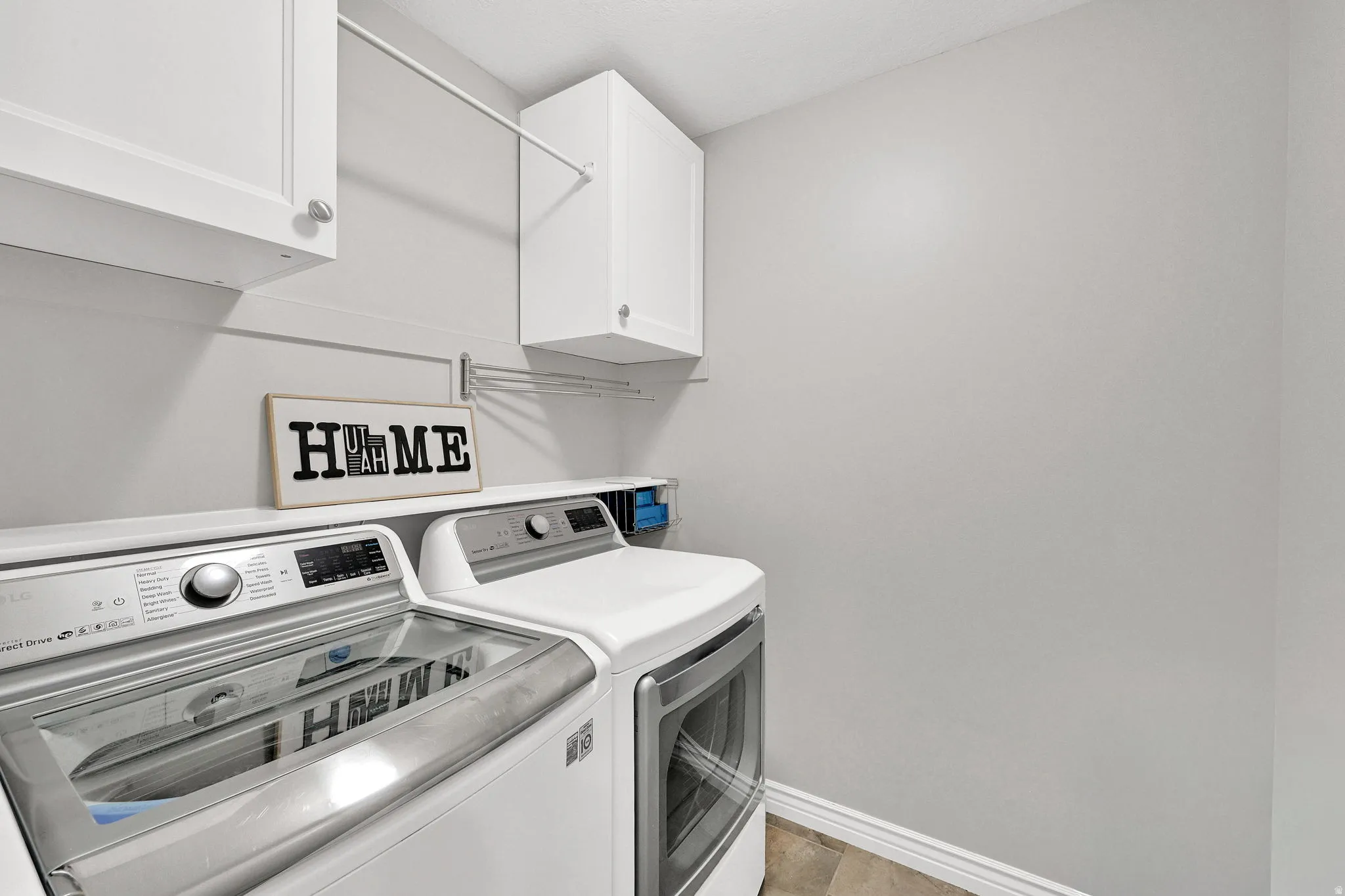 White cabinetry, hanging rod, and wall-mounted shelving in a dedicated utility space