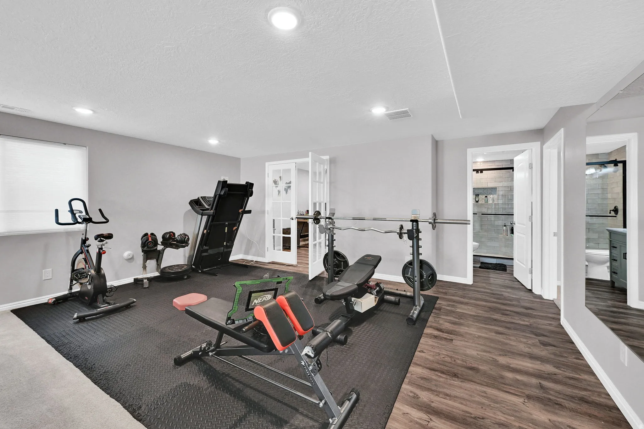 Recessed lighting, wood-finish flooring, and a mirrored wall panel