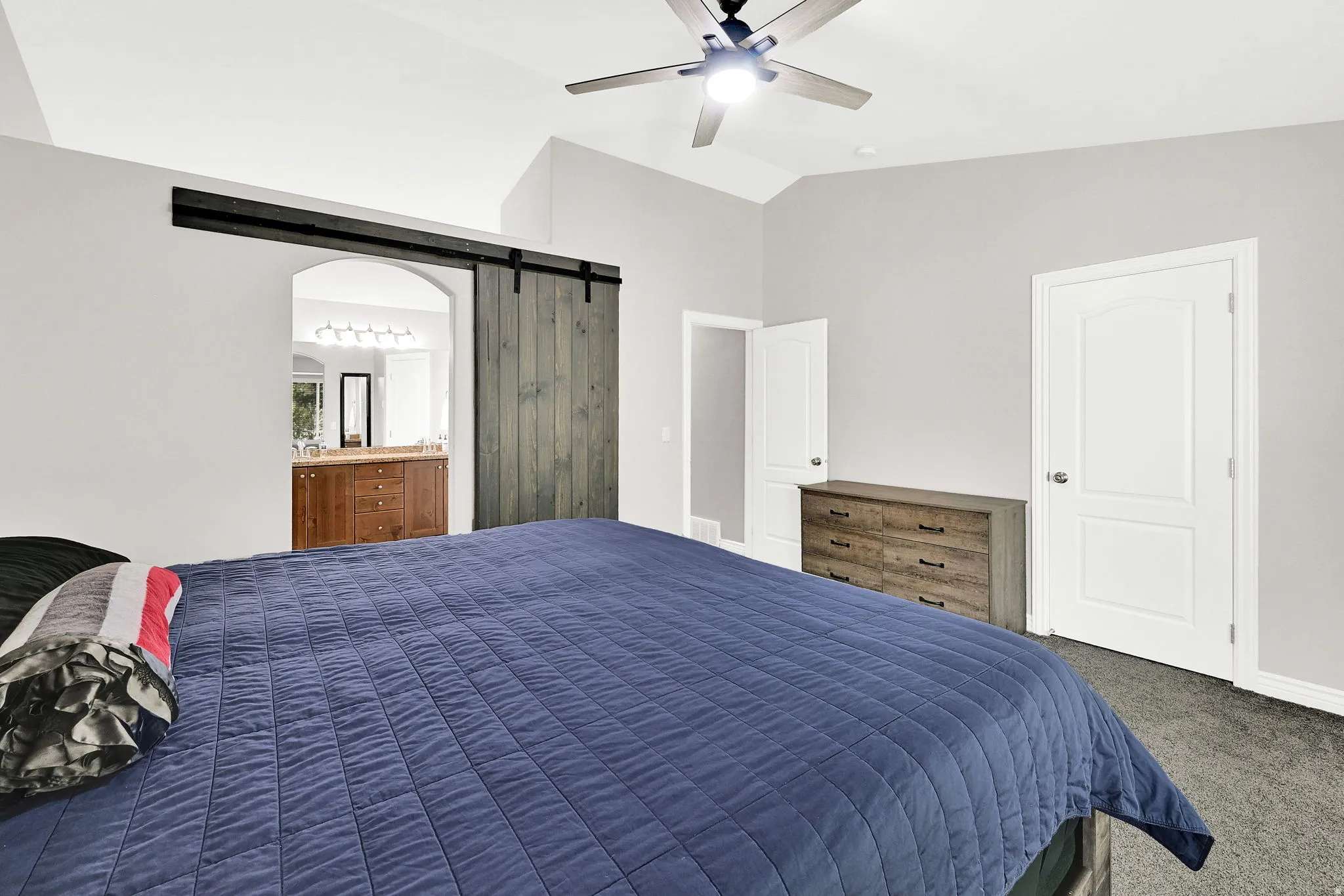 Vaulted ceiling with a ceiling fan, recessed lighting, and a sliding barn door