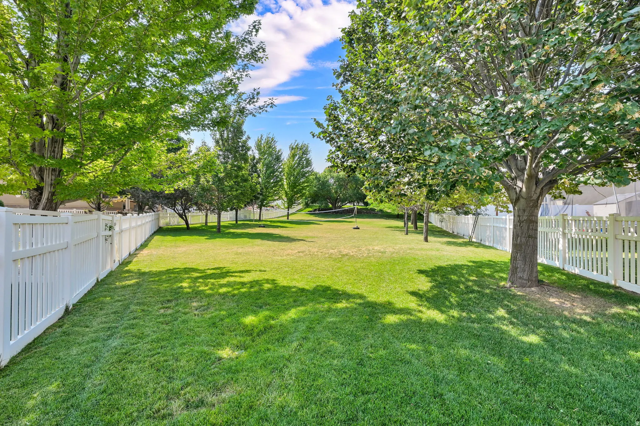 Expansive green lawn framed by mature trees and white picket fencing