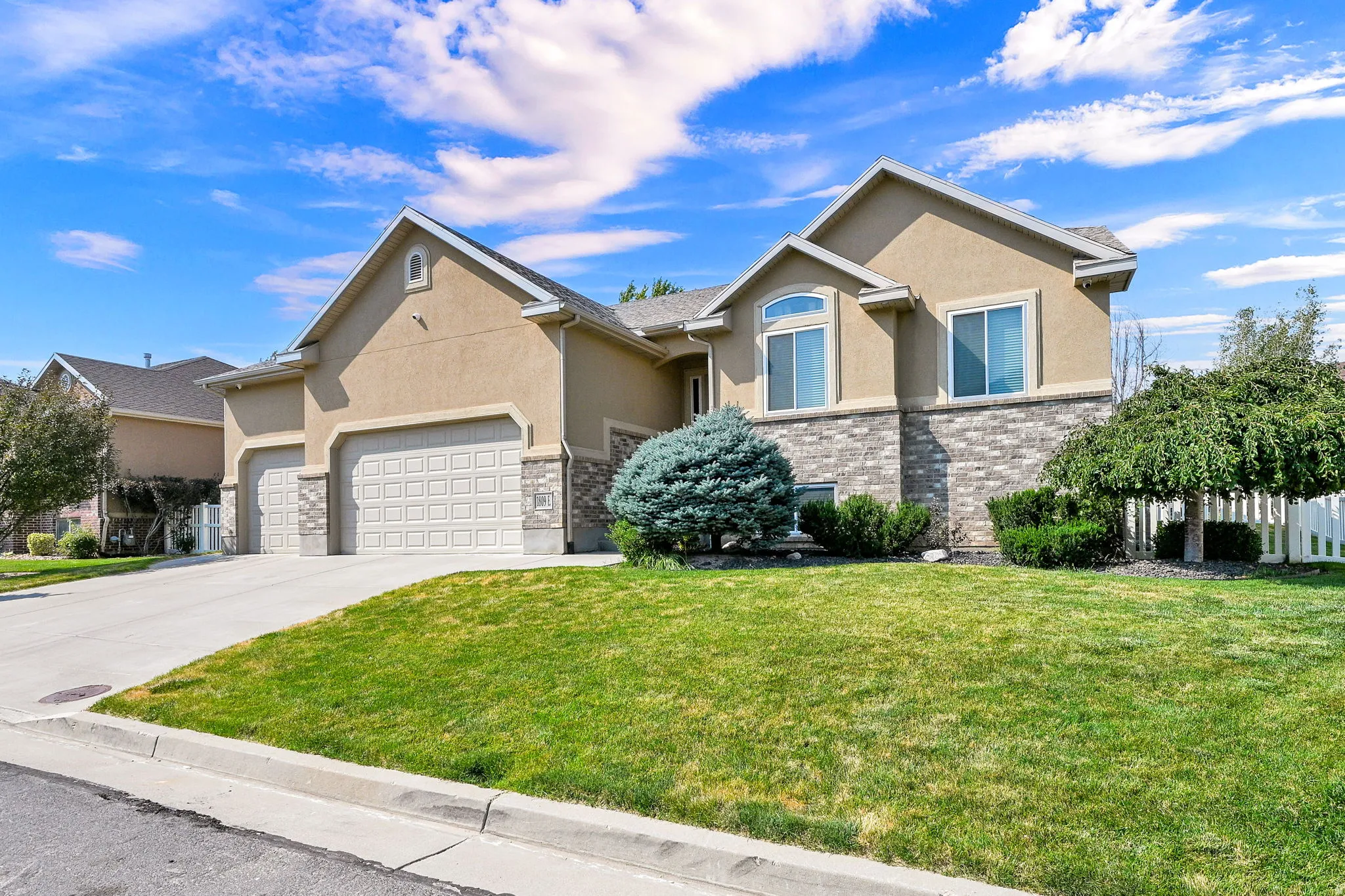 Stucco exterior with stone accenting, arched window, and two-car garage
