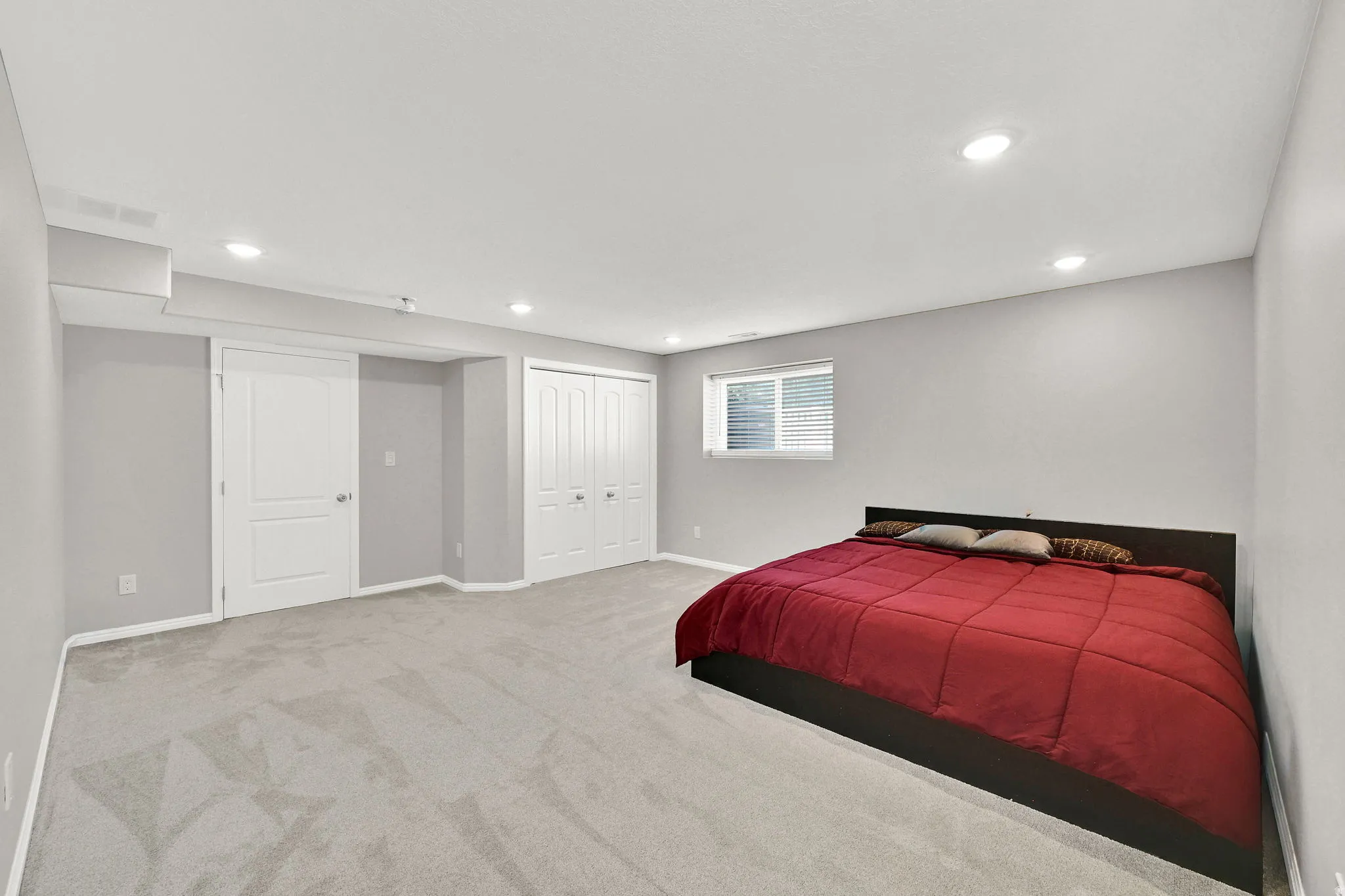 Recessed lighting illuminates the carpeted flooring and light grey walls