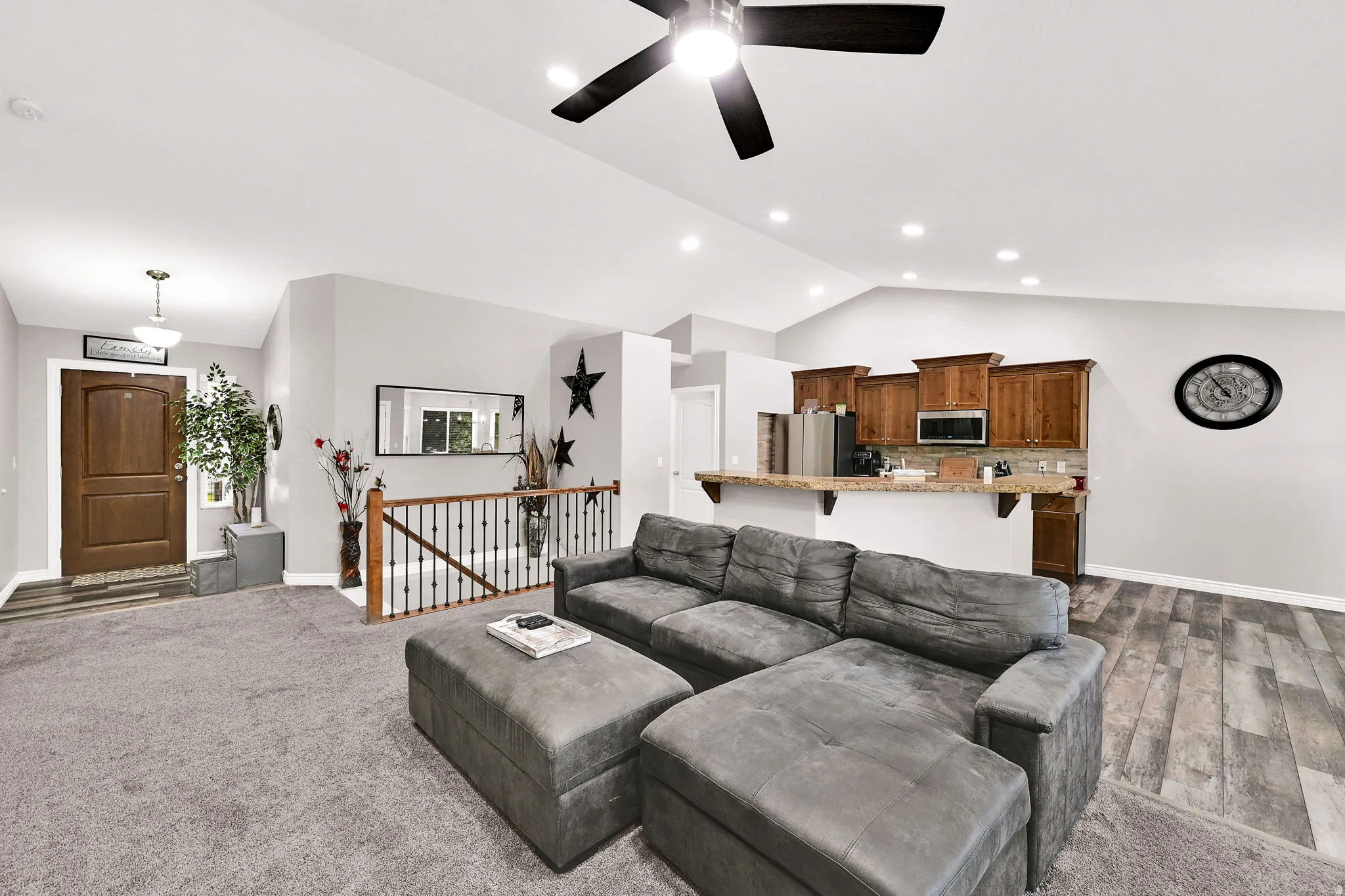 Vaulted ceilings, recessed lighting, and a ceiling fan enhance the living area